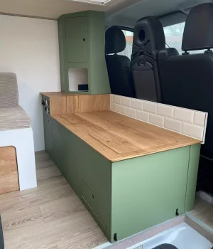 Vue d'ensemble de la cuisine en chêne avec mobilier vert réalisée sur mesure dans un Renault Trafic aménagé L2H1