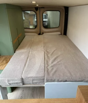 Lit peigne déployé offrant un grand couchage de 190x120 dans un aménagement sur mesure de Renault Trafic L2H1.