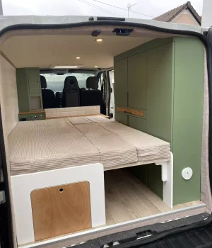 Vue arrière du Renault Trafic aménagé avec lit peigne avec coffre en partie basse, grand placard de rangement et mobilier sur mesure.