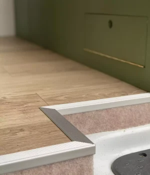 Marche d'accès habillée avec revêtement de sol et seuil aluminium dans un aménagement de van sur mesure.