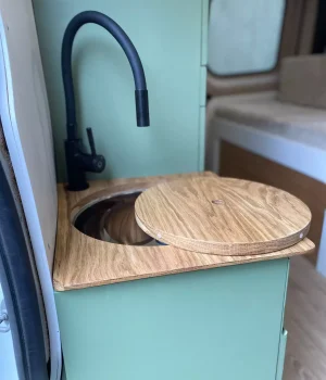 Meuble lavabo avec robinet noir et couvercle en chêne dans un Renault Trafic aménagé L2H1