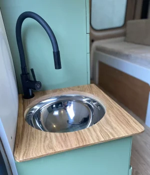 Meuble lavabo avec robinet noir et couvercle en chêne dans un Renault Trafic aménagé L2H1