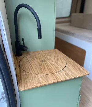 Meuble lavabo avec robinet noir et couvercle en chêne dans un Renault Trafic aménagé L2H1