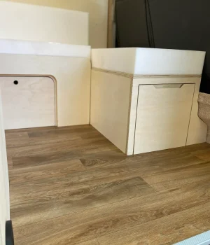 Banquette convertible avec coffre de rangement intégré dans un aménagement de van sur mesure.