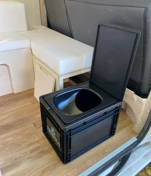 Toilettes sèches amovibles avec rangement dédié sous la banquette d'un van aménagé.