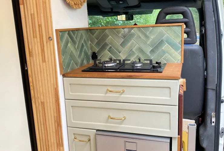 Cuisine sur mesure avec réfrigérateur, plaque de cuisson et grands tiroirs dans un fourgon aménagé haut de gamme.