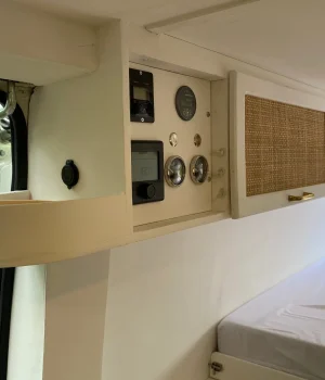 Meuble haut en cannage avec panneau de commande électrique et vide-poches intégrés dans un aménagement de fourgon.
