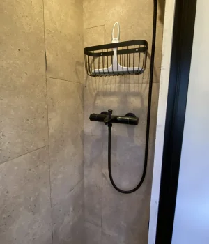 Douche à l'italienne avec colonne de douche, mur en travertin et sol en galets dans un fourgon aménagé.