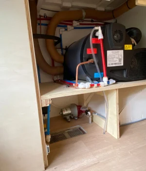 Compartiment technique avec chauffage, chauffe-eau, pompe à eau et vase d'expansion intégrés dans la soute.